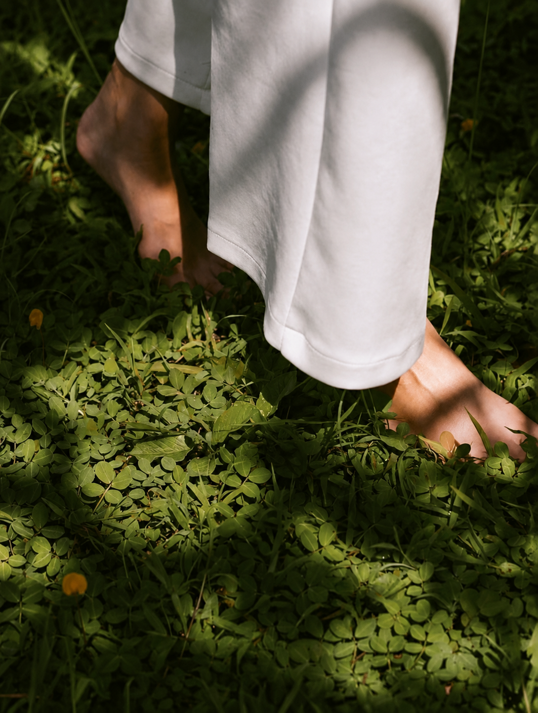 A person walking barefoot through fresh green grass