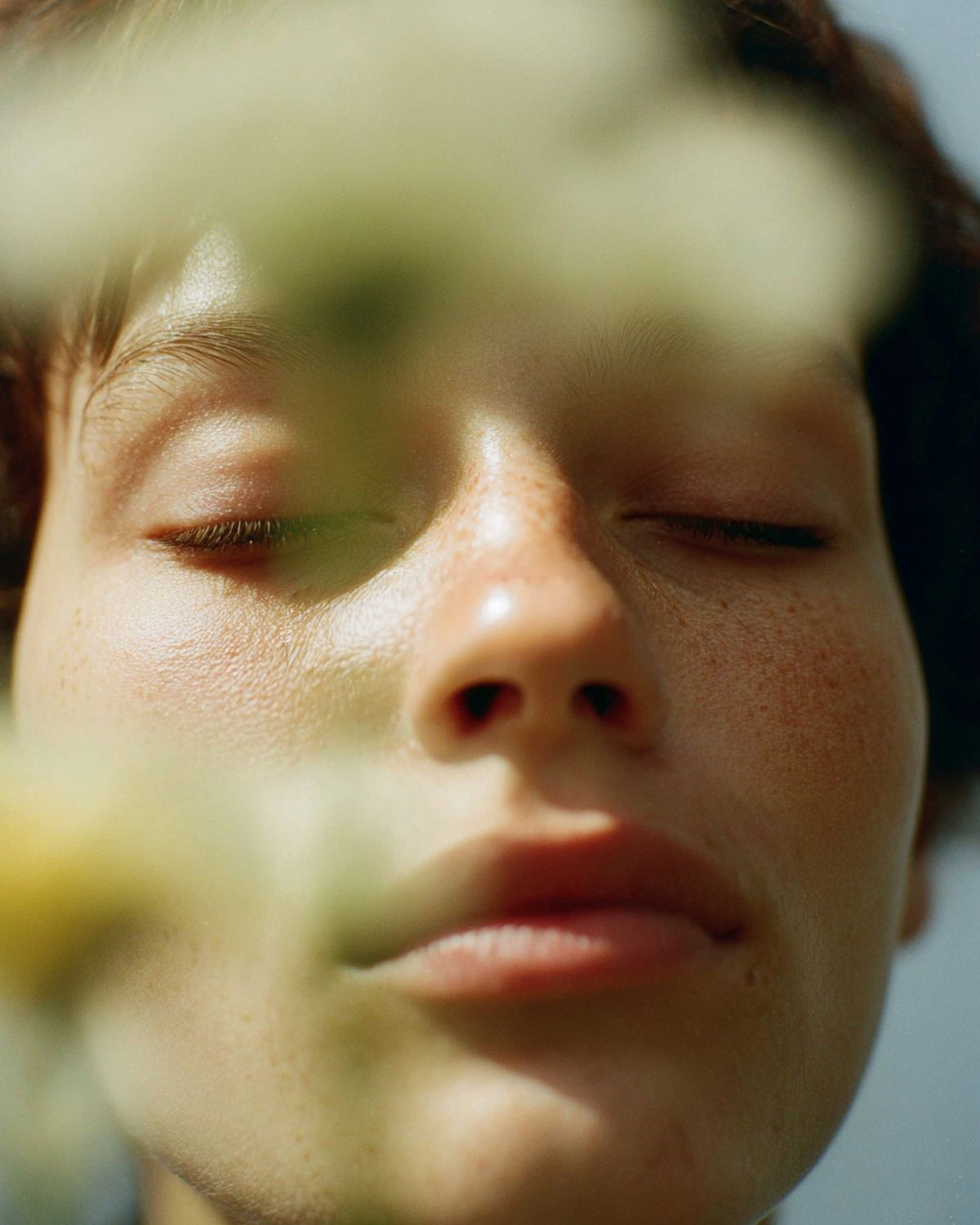 A face half-hidden by leaves, eyes closed in calm